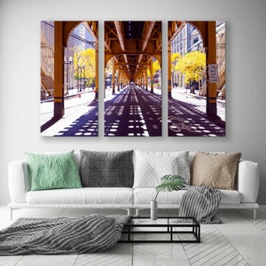 May include: A three-panel photo print of a city street with a yellow metal overpass. The street is lined with trees and the overpass casts shadows on the pavement. The sign reads "May Use Full Lane".