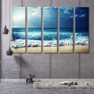 K&ouml;nnte beinhalten: Ein f&uuml;nfteiliger Leinwanddruck, der eine Meereslandschaft mit blauen Ozeanwellen zeigt, die an einem Sandstrand brechen. Der Himmel ist hellblau mit wei&szlig;en Wolken.