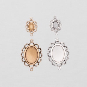 May include: Four oval-shaped pendant settings in antique gold and silver tones. Each setting features a decorative scalloped edge and two small loops for attaching to a chain or other jewelry components. The settings are empty, ready for embellishment.