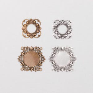May include: Four ornate metal jewelry findings in gold and silver tones. Two have open centers, while the other two have a circular base. Each finding features a detailed, symmetrical design with floral and scrollwork elements, perfect for crafting.