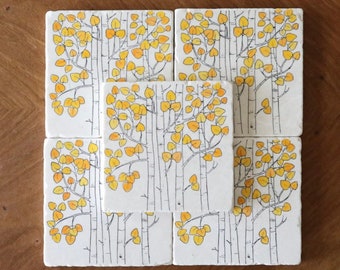 May include: Set of six white ceramic coasters with a black and yellow design of aspen trees with yellow leaves.