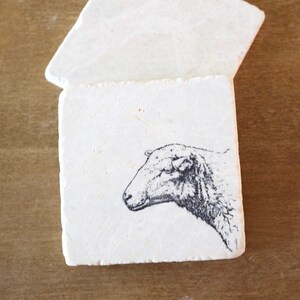 May include: A white ceramic mug with a black handle and the text "But First, Coffee" in a black, handwritten font. The mug is on a white surface.