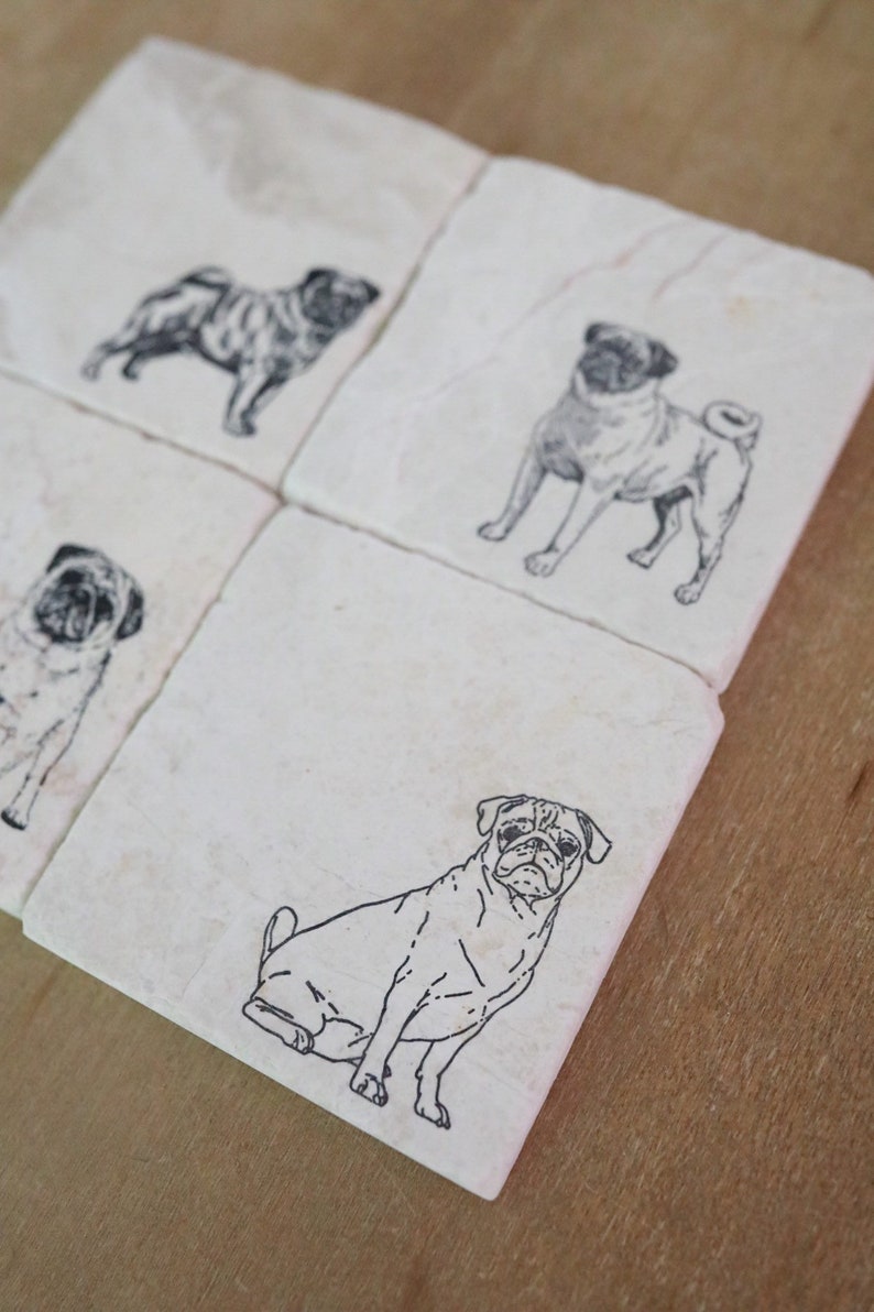 May include: Set of four white ceramic coasters with black line drawings of pugs. Each coaster features a different pose of a pug.