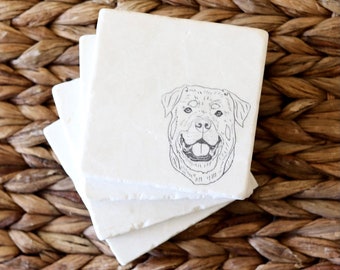 May include: A stack of three square, off-white coasters. Each coaster features a detailed black and white illustration of a dog's face. The coasters are stacked on top of each other, showcasing the dog's smiling face.