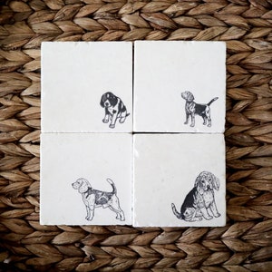 May include: Set of four white ceramic coasters with black and white illustrations of beagles. Each coaster features a different pose of the dog.