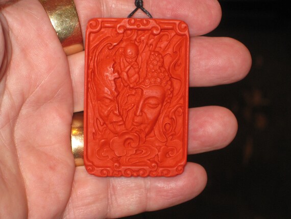 Hand carved red organic cinnabar Buddha and devil head pendant.
