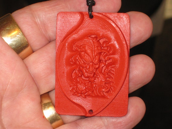 Hand carved red organic cinnabar devil pendant.