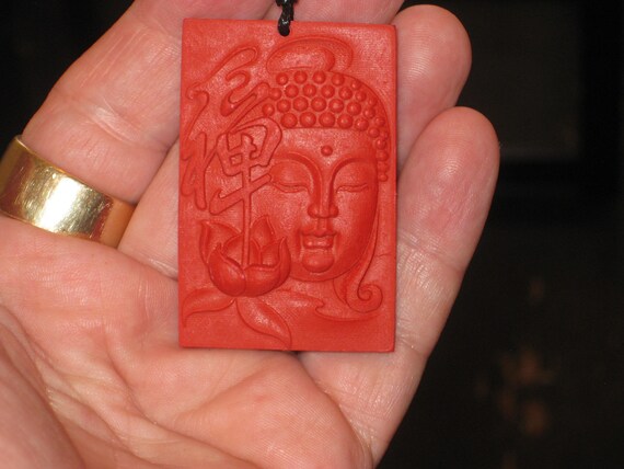 Hand carved red organic cinnabar Buddha pendant.
