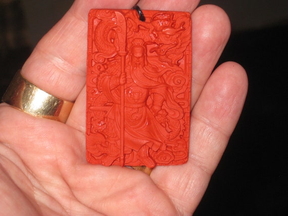 Hand carved red organic cinnabar warrior and dragon pendant.