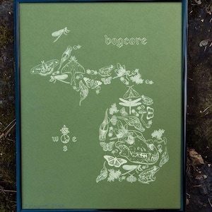 May include: Framed art print featuring a green background with a white illustration of the state of Michigan, filled with insects and the word "bogcore". Includes a compass rose and a variety of insects.