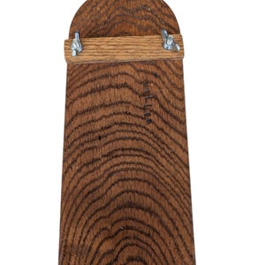 May include: A wooden cutting board with a curved top and a rectangular base. The board is made of dark brown wood with visible grain patterns. A light brown wooden bar is attached with metal hardware. The word "MILLER" is etched into the wood.