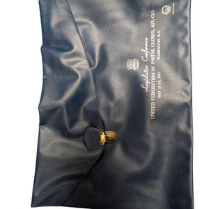 May include: A navy blue leather document case with a gold-colored clasp. The case features the text "Legislative Conference UNITED FEDERATION OF POSTAL CLERKS, AFL-CIO MAY 15-17, 1967 WASHINGTON, D.C." in white lettering.