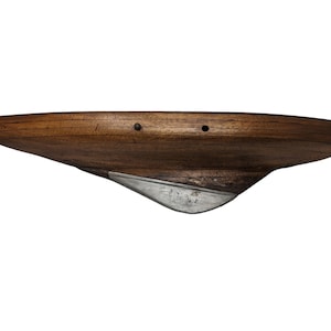 Könnte beinhalten: Ein gebogenes Holzregal in Dunkelbraun mit einem silberfarbenen Metallakzent. Das Regal hat eine aerodynamische Form und zwei kleine Löcher in der Oberseite. Die Länge des Regals beträgt ca. 60 cm.