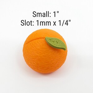 May include: An orange-colored, spherical object with a textured surface and a green leaf. The object has a slot cut into it. Text on the image reads "Small: 1"" and "Slot: 1mm x 1/4""
