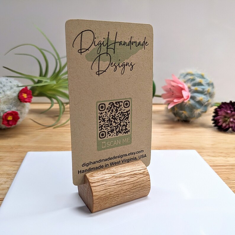 May include: A brown business card with the text "DigiHandmade Designs" and a QR code with the text "SCAN ME" below it. The card is on a wooden stand and the text below the QR code reads "digihandmadedesigns.etsy.com Handmade in West Virginia, USA."