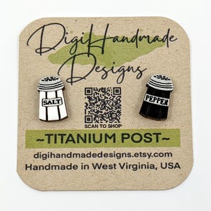 May include: Salt and pepper shaker earrings on a brown card. The salt shaker is white with black accents and the word "SALT". The pepper shaker is black with white accents and the word "PEPPER". The card has the text "Digi Handmade Designs".