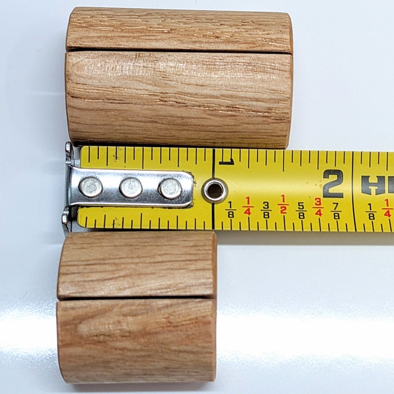May include: Two wooden dowel rods with a groove in the center, measured with a tape measure that reads "2 H 2 7 8 3 4 5 8 1 4 1 8".