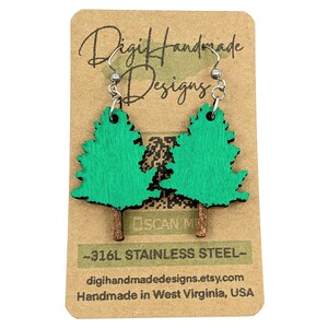May include: Green wooden earrings shaped like pine trees with brown stems. The earrings are on a brown card with the text "Digihandmade Designs" and "~316L Stainless Steel~" in black. The card also includes the text "digihandmadedesigns.etsy.com" and "Handmade in West Virginia, USA".