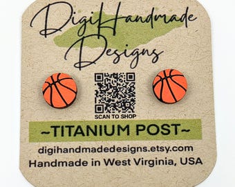 May include: A pair of orange and black basketball-themed earrings with titanium posts. The earrings are displayed on a card with the text "Digi Handmade Designs" and a QR code that says "Scan to Shop". The card also includes the text "Titanium Post" and "digihandmadedesigns.etsy.com". The card also includes the text "Handmade in West Virginia, USA".