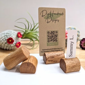May include: Four wooden card holders, two are stacked on top of each other, and two are standing upright. The card holders are made of natural wood and have a rounded shape. A business card is displayed in one of the card holders. The business card has a QR code and the text "Digi Handmade Designs, digihandmade designs.etsy.com, Handmade in West Virginia, USA". Another card is displayed in a card holder and has the text "Sammy L."
