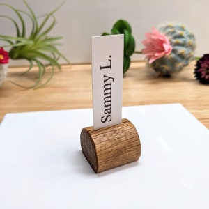 May include: A wooden place card holder with a rounded top and a white card that reads "Sammy L."
