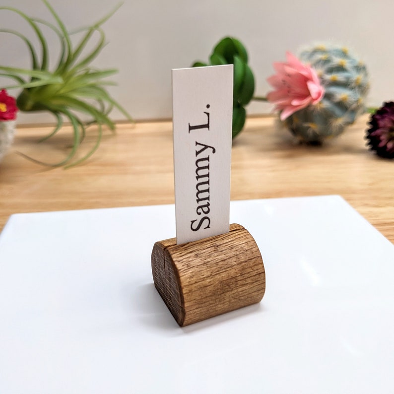May include: A wooden place card holder with a rounded top and a white card that reads "Sammy L."