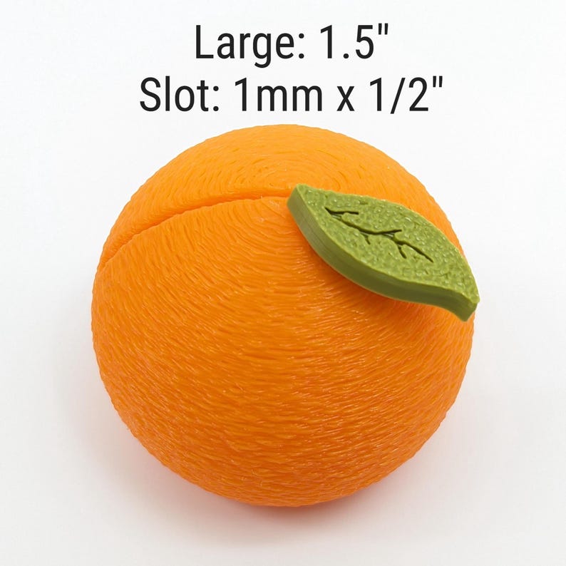 May include: An orange-colored, spherical object with a textured surface and a green leaf attached. The text "Large: 1.5" and "Slot: 1mm x 1/2" is displayed above the object. The object is likely a decorative item or craft supply.