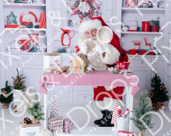 May include: Santa Claus in a red suit and hat, standing behind a table with a red and white checkered tablecloth. The table holds a gingerbread house, candy, and a mixing bowl. Shelves in the background are decorated with Christmas items.