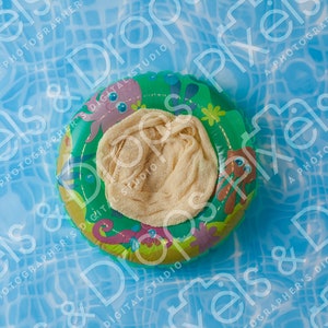 Op de afbeelding: Een groene en gele opblaasbare zwemband met een witte stoffen inzet. De band is bedrukt met verschillende kleurrijke zeedieren.