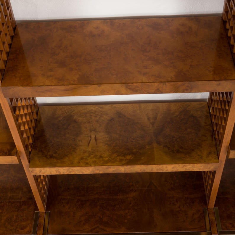 K&ouml;nnte beinhalten: Ein B&uuml;cherregal aus Holz mit mehreren Regalbrettern und einem geometrischen Muster an den Seiten. Die Regalbretter sind aus hellem braunem Holz mit nat&uuml;rlicher Holzmaserung.