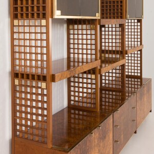 K&ouml;nnte beinhalten: Eine modulare Holzwand-Einheit mit einem geometrischen Gitterdesign. Die Einheit verf&uuml;gt &uuml;ber mehrere Regale, Schr&auml;nke und Glast&uuml;ren. Das Holz hat eine satte braune Farbe und eine nat&uuml;rliche Maserung.