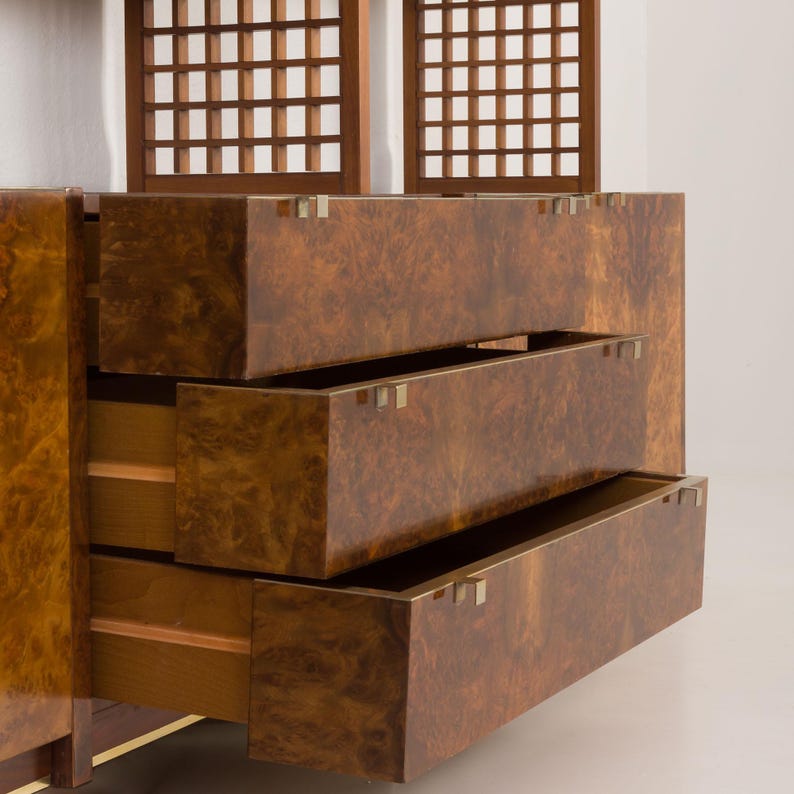 K&ouml;nnte beinhalten: Ein Holzschr&auml;nkchen mit drei offenen Schubladen. Die Schubladen sind aus Holzfurnier in Braun- und Goldt&ouml;nen gefertigt. Der Schrank hat ein schlichtes Design mit Messingbeschl&auml;gen.
