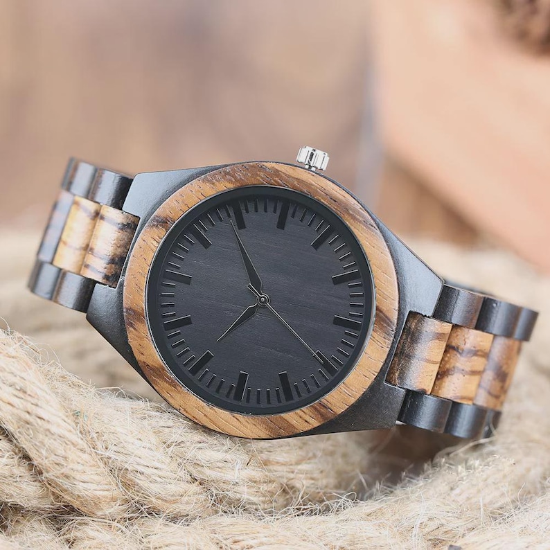 May include: A wristwatch featuring a round face with a black dial and thin hands, encased in a bezel of light brown wood. The link bracelet alternates between dark black wood and light brown wood segments, with a silver crown on the side.