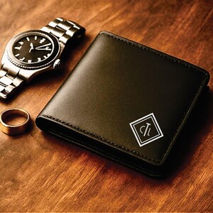 Black leather bifold wallet with a white geometric monogram design featuring the initials “CL” in the bottom corner, displayed on a warm wooden surface beside a silver wristwatch and a gold ring for a classy, masculine presentation.