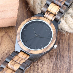 May include: A black and brown wooden wristwatch with a black face and silver hands. The watch has a wooden band with a striped pattern.