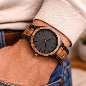 May include: A wristwatch featuring a round face with a matte black dial and thin black hands. The watch case and the central links of the bracelet are crafted from dark wood, while the outer bracelet links are made of a lighter, textured wood.