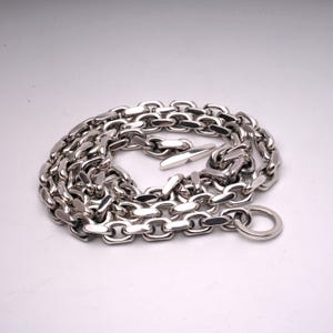 May include: A silver chain necklace with a toggle clasp and a ring pendant.