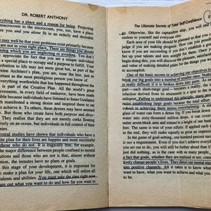 May include: An open book with text on aged paper. The pages are from a book titled "Dr. Robert Anthony" and "The Ultimate Secrets of Total Self-Confidence". The text is highlighted with blue ink. The book is open to pages 116 and 117.