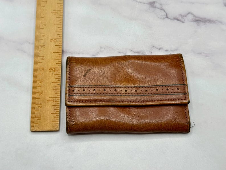 May include: A brown leather wallet with a stitched design and a flap closure.