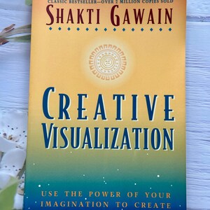 May include: A book titled "Creative Visualization" by Shakti Gawain. The cover has a gradient background of yellow, green, and blue. The title is in large blue letters. The book is a revised edition of a classic bestseller.