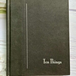 May include: A dark green book with the title "Ten Things" in white lettering. A vertical white line is on the left side of the cover. The book has a textured cover.