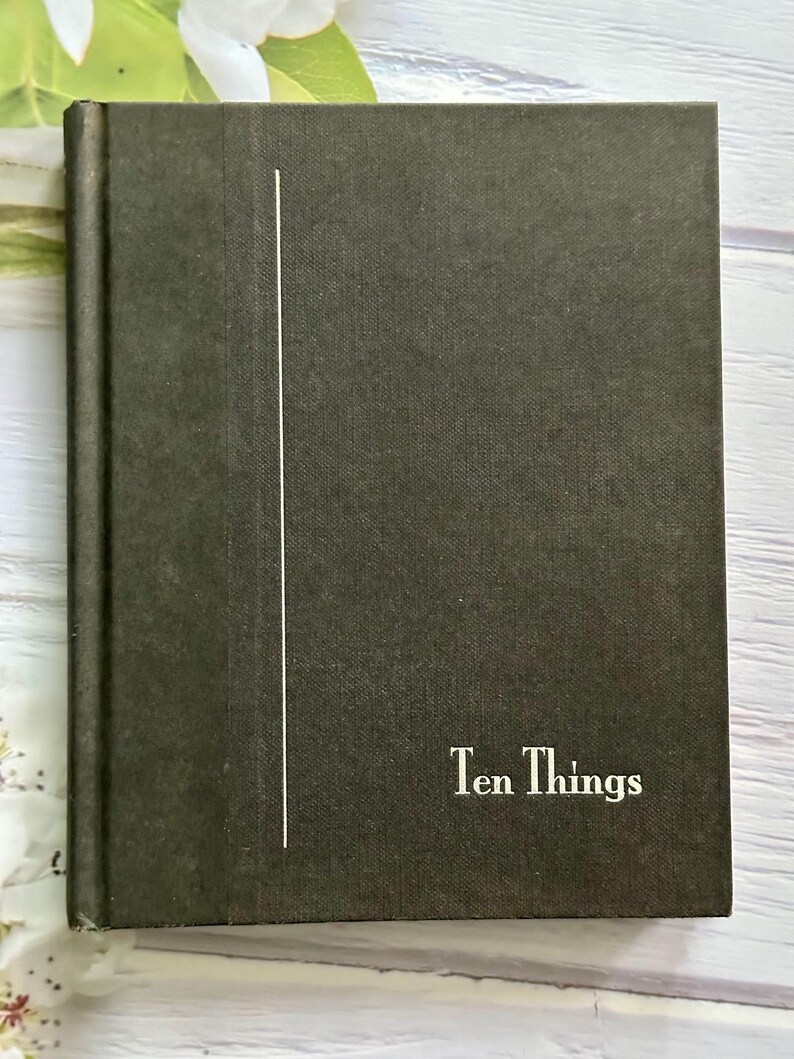 May include: A dark green book with the title "Ten Things" in white lettering. A vertical white line is on the left side of the cover. The book has a textured cover.