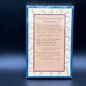 May include: A blue and white book cover with the title "Your Fortune is in Your Numbers!" by Karen David. The cover features a colourful design of numbers and a quote about the author's work.