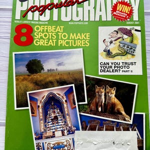 May include: A vintage August 2001 issue of Popular Photography magazine. The cover is green and features the magazine's logo, images of cameras, and the text "8 Offbeat Spots to Make Great Pictures." Additional text includes "Can You Trust Your Photo Dealer? Part II."