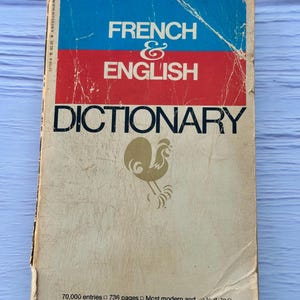 May include: Vintage "The Bantam New College French & English Dictionary." The cover features blue, red, and white sections with the title in bold white letters. A gold rooster illustration is visible. The book has 70,000 entries and 736 pages.