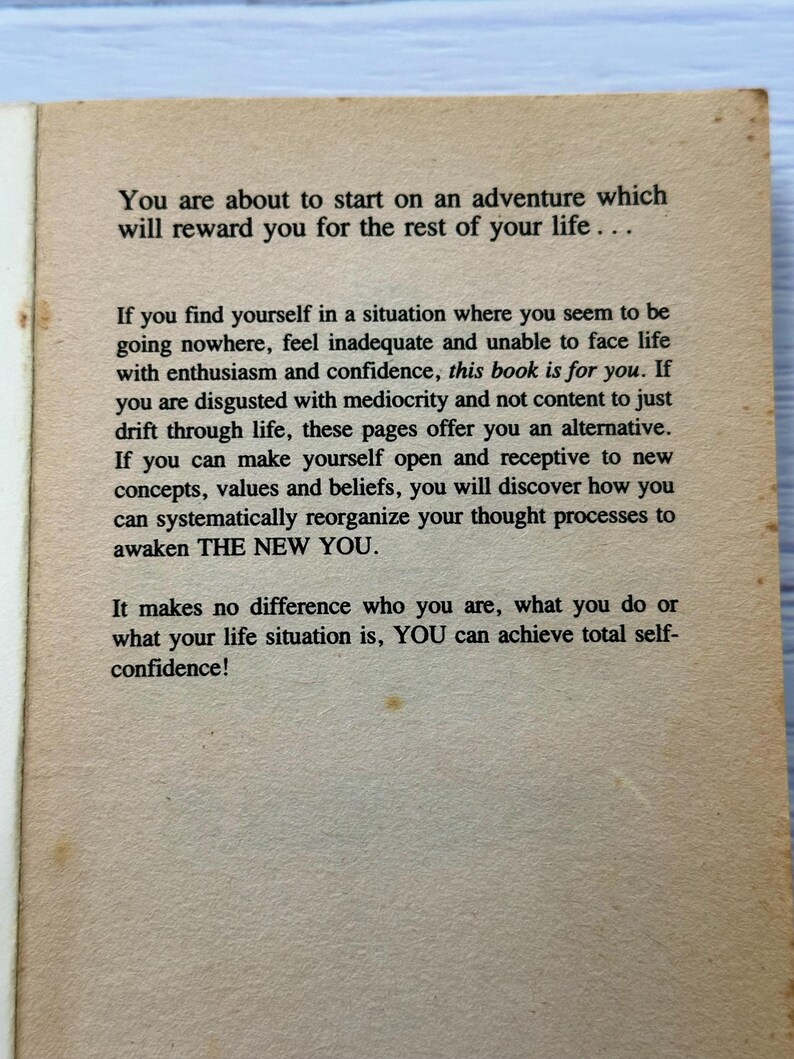 May include: Aged book page with text about self-improvement. The text reads, "You are about to start on an adventure which will reward you for the rest of your life..." The page has a light brown colour.