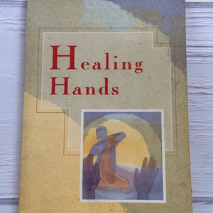 May include: A book titled "Healing Hands" by Allegra Taylor. The cover features the text in red, with the title over an illustration of hands and a figure. The book is part of the "Tuttle Alternative Health" series.
