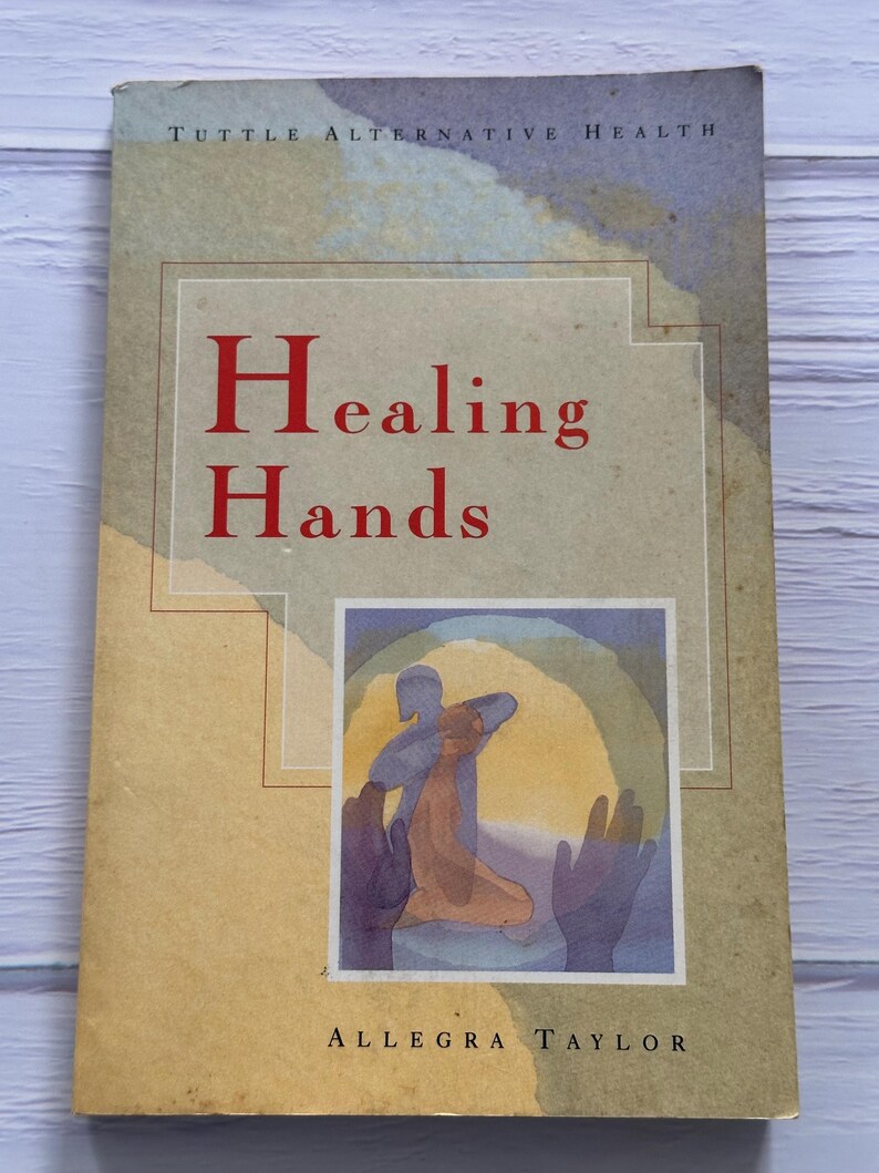 May include: A book titled "Healing Hands" by Allegra Taylor. The cover features the text in red, with the title over an illustration of hands and a figure. The book is part of the "Tuttle Alternative Health" series.