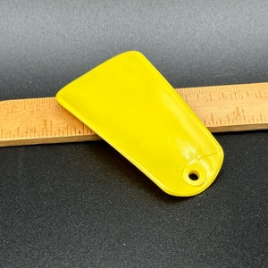 May include: A yellow plastic shoe horn with a hole at the end. The shoe horn is about 4 inches long.