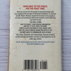 May include: A well-worn paperback book titled "Total Self-Confidence" is displayed. The cover includes the text "Available to the Public for the First Time" and a list of topics. The ISBN is 0-425-10170-3. The book shows signs of age.